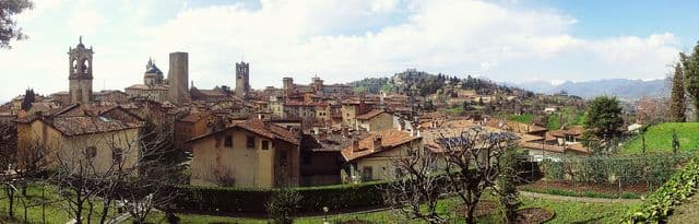 Panoramic skyline view of Città Alta hilltop towers, domes, and bell towers in Bergamo