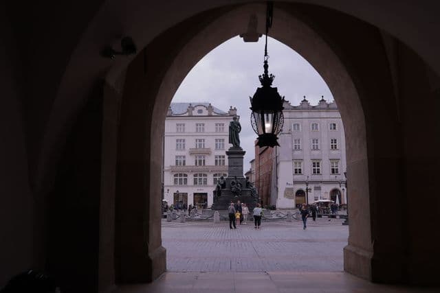 View of the Adam Mickiewicz Monument in Krakow's historic Old Town, showcasing the city's architectural charm.