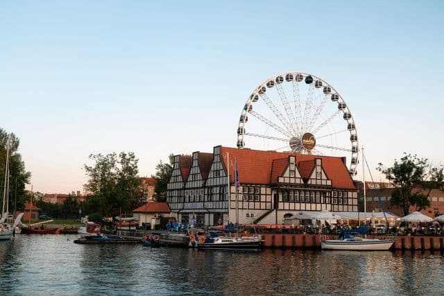Charming evening view of the Ferris wheel and historic buildings by the water in Gdańsk, Poland.