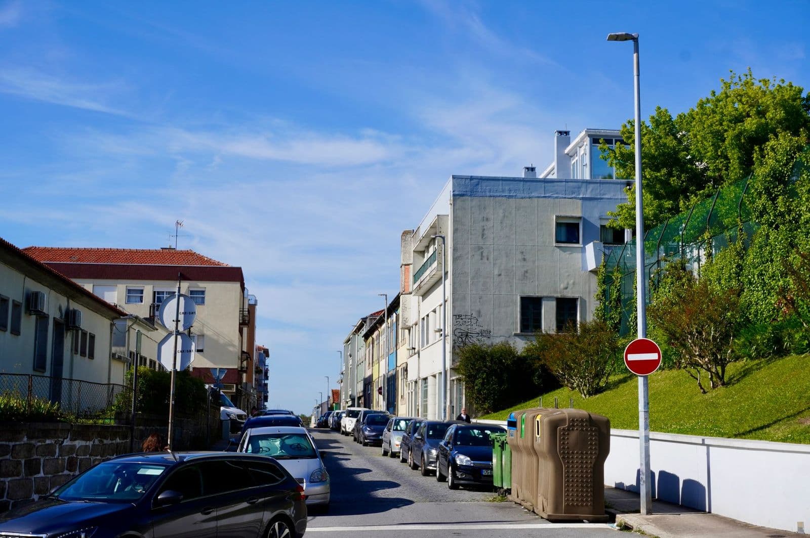 Street view of residential buildings and parked cars in Porto, Portugal on a sunny day.