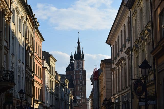 Charming Krakow street with St. Mary's Basilica, capturing historic architecture under a bright sky.