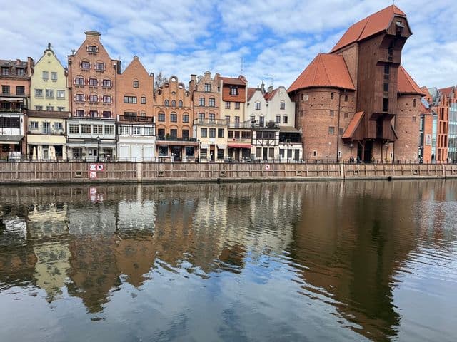 Beautiful reflection of historic Gdańsk architecture along the Motława River on a clear day.