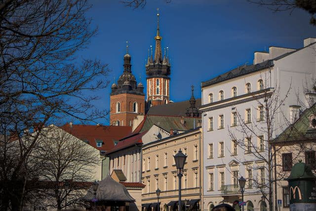 Vibrant view of St. Mary's Basilica and charming Kraków architecture under a clear blue sky.