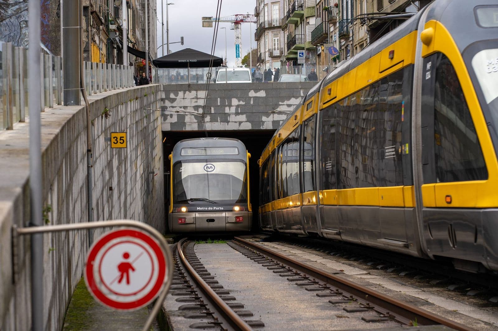 Porto metro train exiting a city tunnel with urban architecture and street signs.