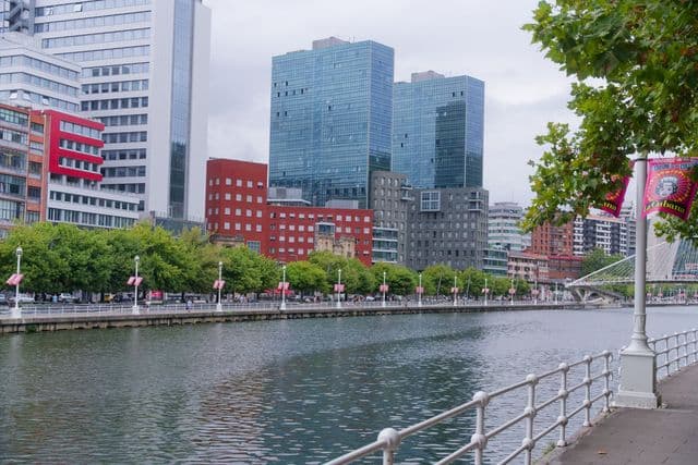 Modern buildings and riverfront promenade in Bilbao, showcasing unique urban design.