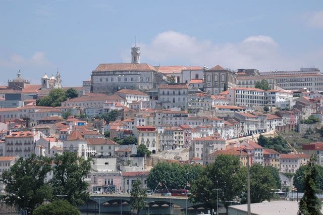 Explore Coimbra's stunning historic architecture with vibrant red rooftops and lush greenery.